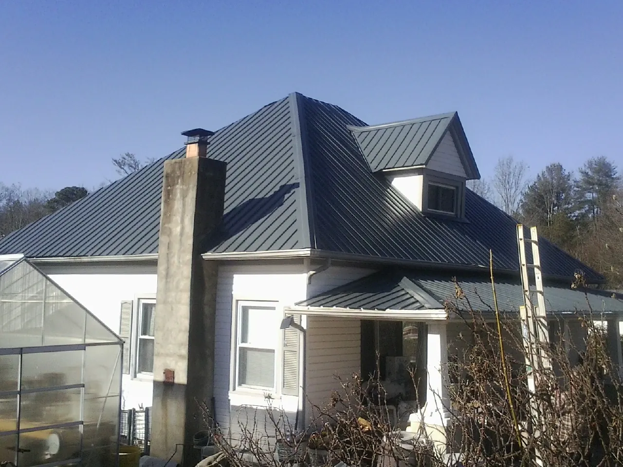 Dark blue standing seam metal roof on a white farmhouse with dormer — Slate & Tile Roof Repair by Roofing Brothers in South Woodstock