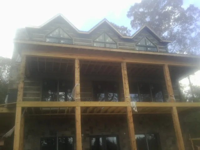 Dormers and porch framing on a large log home under construction — Roof Coating work by our crew in South Woodstock