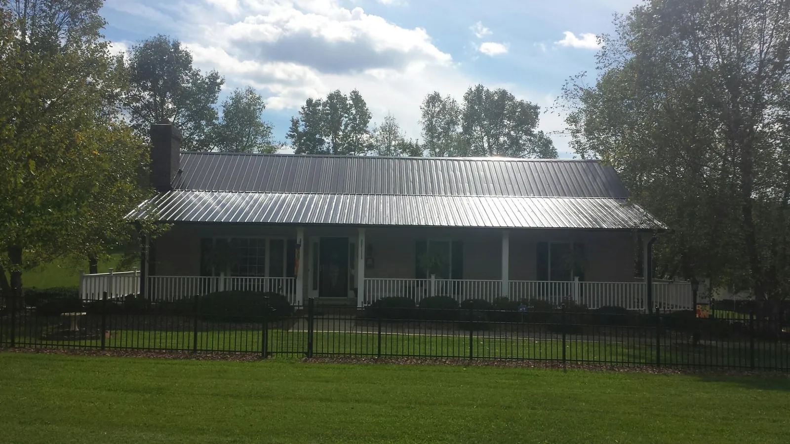 Gray metal roof on a brick ranch with a full width front porch — Gutter Guard Installation work by our crew in South Woodstock