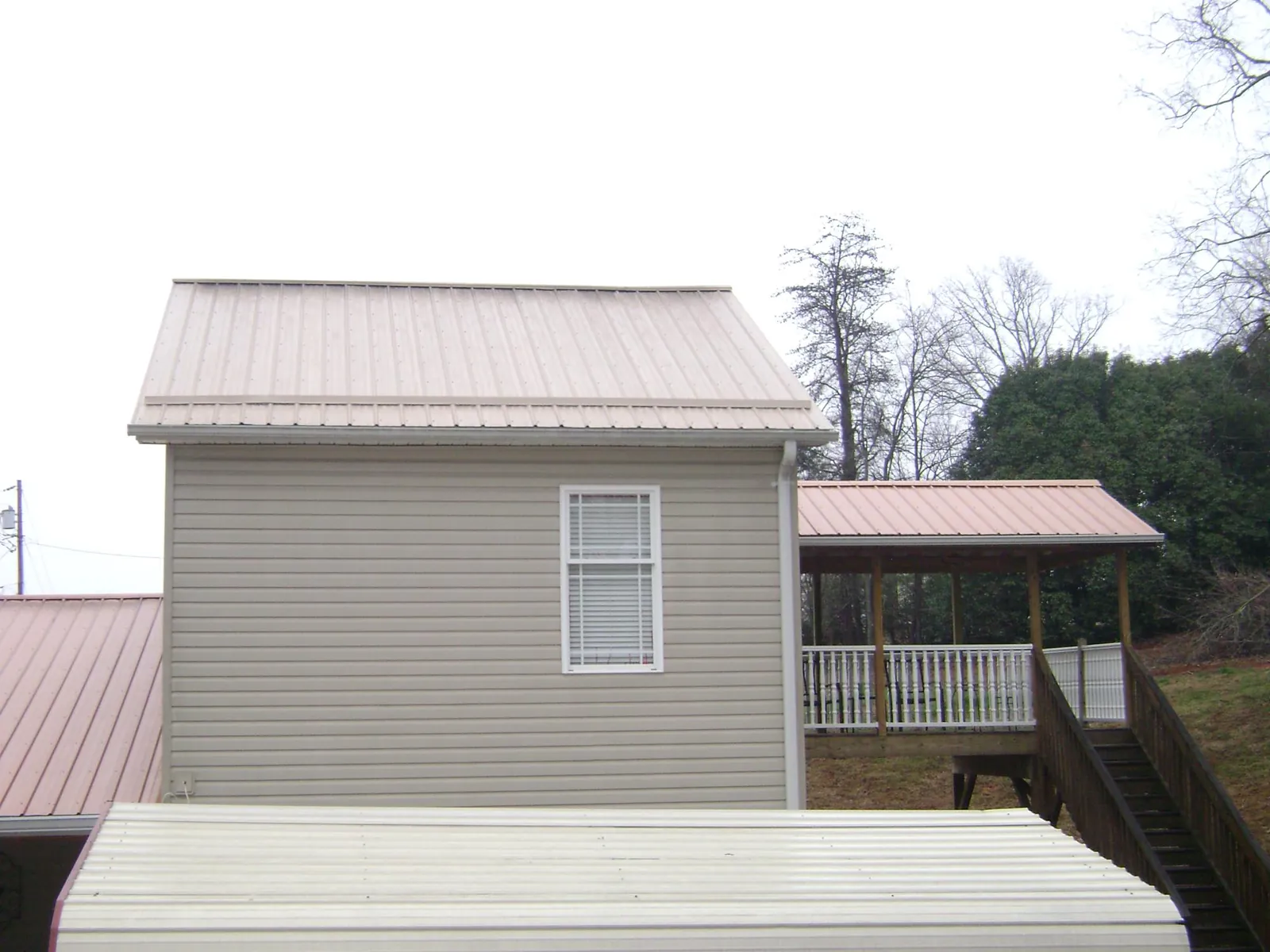 Tan metal roofs on a two story addition and attached porch, from a Roof Replacement job in South Woodstock